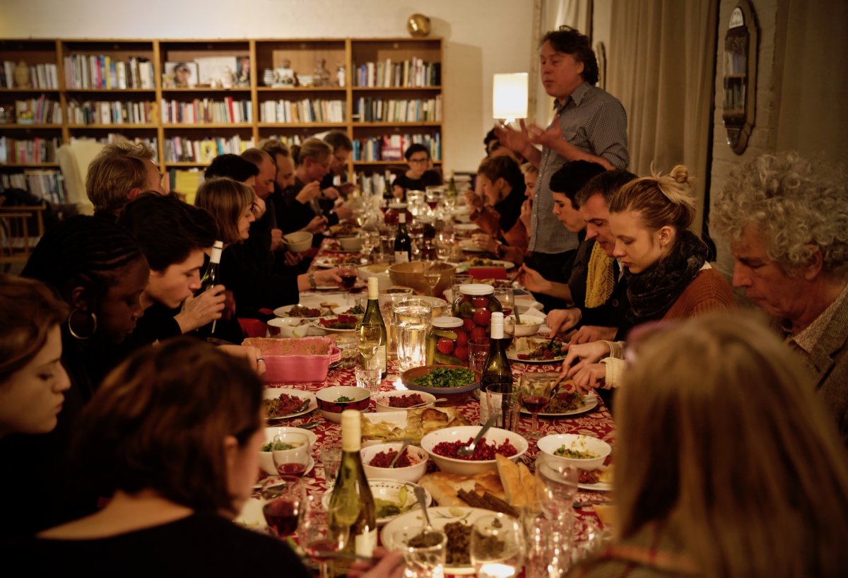 Photo by Nicolai Khalezin a dinner party table filled with guests and food