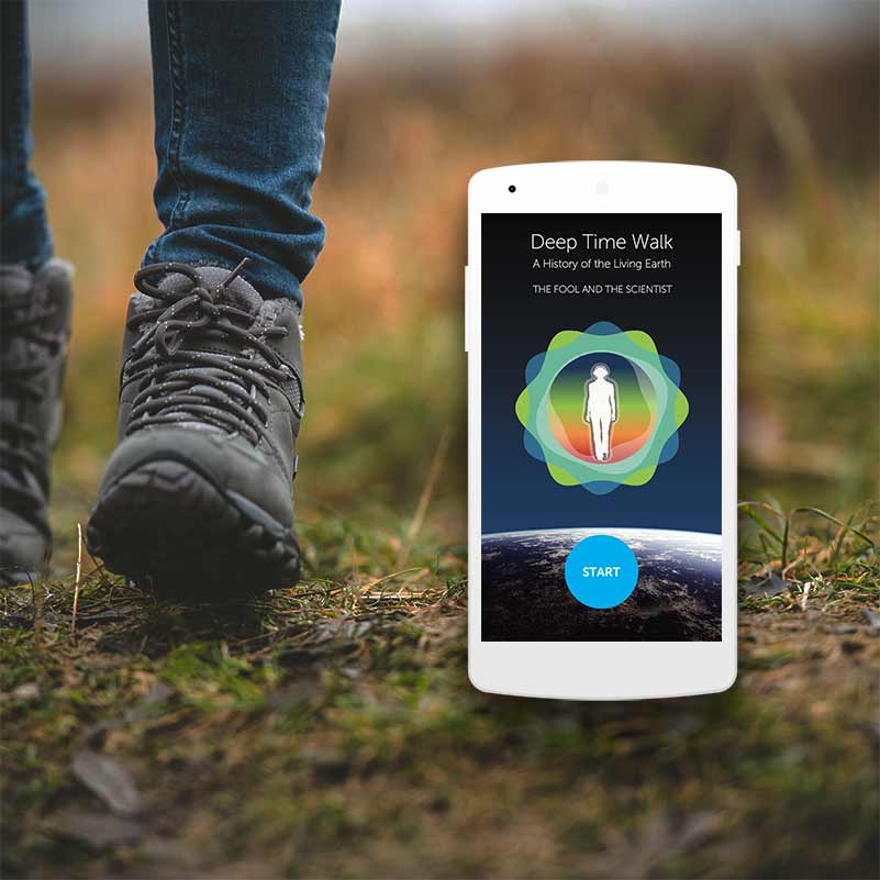 Deep Time Walk Walking boots on grass with a phone and an app imposed in the grass